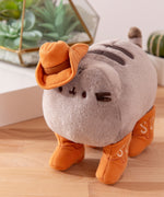 Aerial view of cowboy plush shows Pusheen the Cat's classic two back stripes and striped tail. 