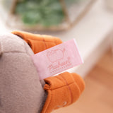 Close-up view of the Pusheen Shop logo tag that is affixed near the bottom of the grey plush.