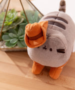 Top aerial view showcasing Pusheen’s fuzzy plush texture, and her brown plush cowboy hat that sits on her right triangular ear. 