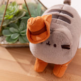 Top aerial view showcasing Pusheen’s fuzzy plush texture, and her brown plush cowboy hat that sits on her right triangular ear. 