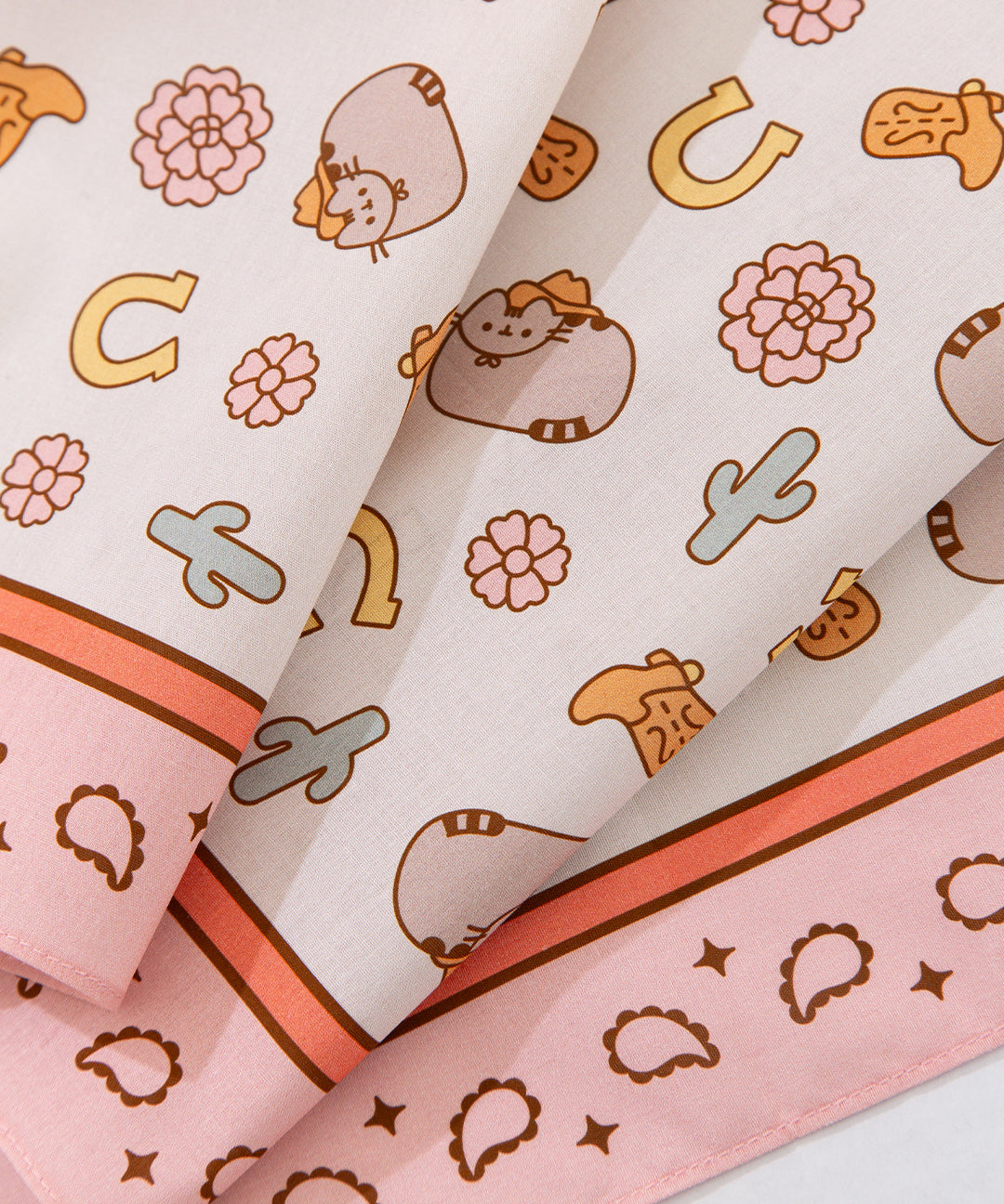 Close-up print of the pusheen cowboy-themed bandana. The light beige scarf has digitally printed brown, grey, yellow, pink, and green graphics.