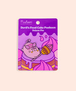 Devil’s Food Cake Pusheen Pin on backer card. The backing card shows many brown, yellow, purple, and pink layered cakes in front of a yellow background. 