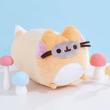 Right side view of the fox Pusheen plush. The orange, white, pink, and grey long plush is surrounded by white, blue, pink, and yellow mini mushrooms. The brown whiskers of the plush extend off of the front of the plush body. 