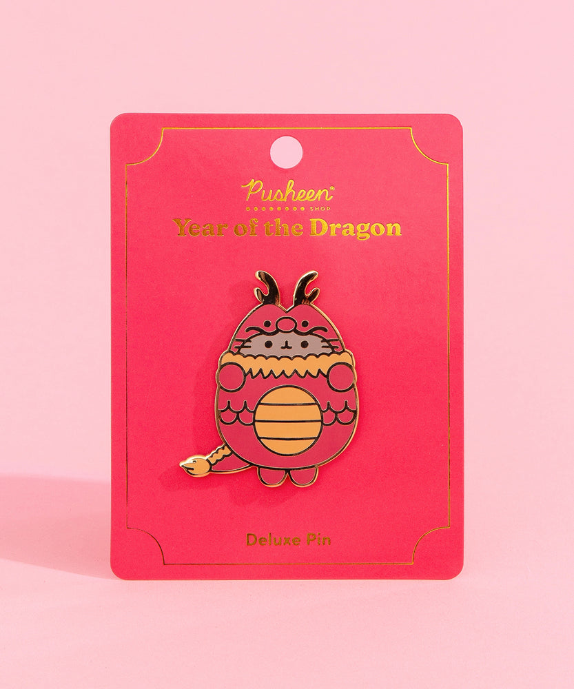 Front view of the Pusheen Year of the Dragon Deluxe Pin. Pusheen the cat wears a red and gold dragon costume. The grey, red, and gold pin has gold plating outlines and is held in the center of a red and gold backer card.