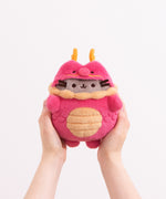 Model holding Lunar New Year Pusheen Dragon Plush to show size scale. The bottom of the plush fits in the models hands while the head and legs are not encompassed by the hands.