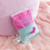 Back view of the bag of chips plush. Pusheen the Cat's striped tail sticks out the back of the blue portion of the bag. The pink top half of the bag features Pusheen's two back stripes embroidered in a medium purple color. 
