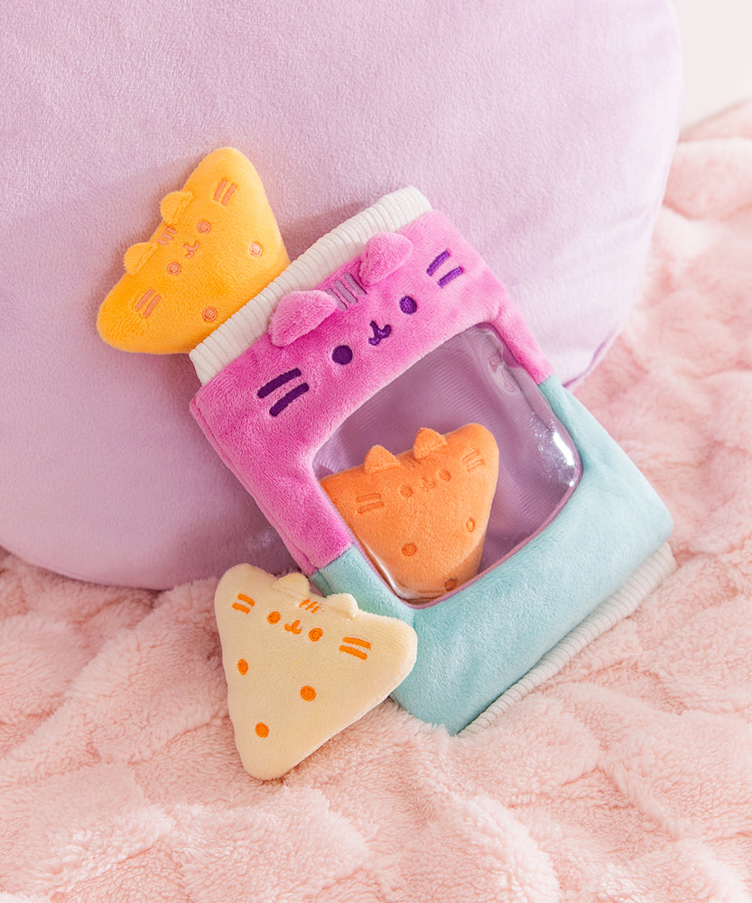 Three plush tortilla chip inspired plush sit in and around the included plush bag. Both the chips plush and bag have Pusheen the Cat's face embroidered on them.