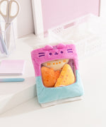 Pusheen Gamer Chips Plush its on a white desktop. The bag features white ribbed edged details on the top and bottom of the  two-toned blue and purple bag.