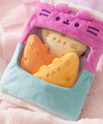 Three plush tortilla chips sit inside the plush bag. The three tortilla chips are in a range of light yellow to golden yellow and feature embroidered spice dots.