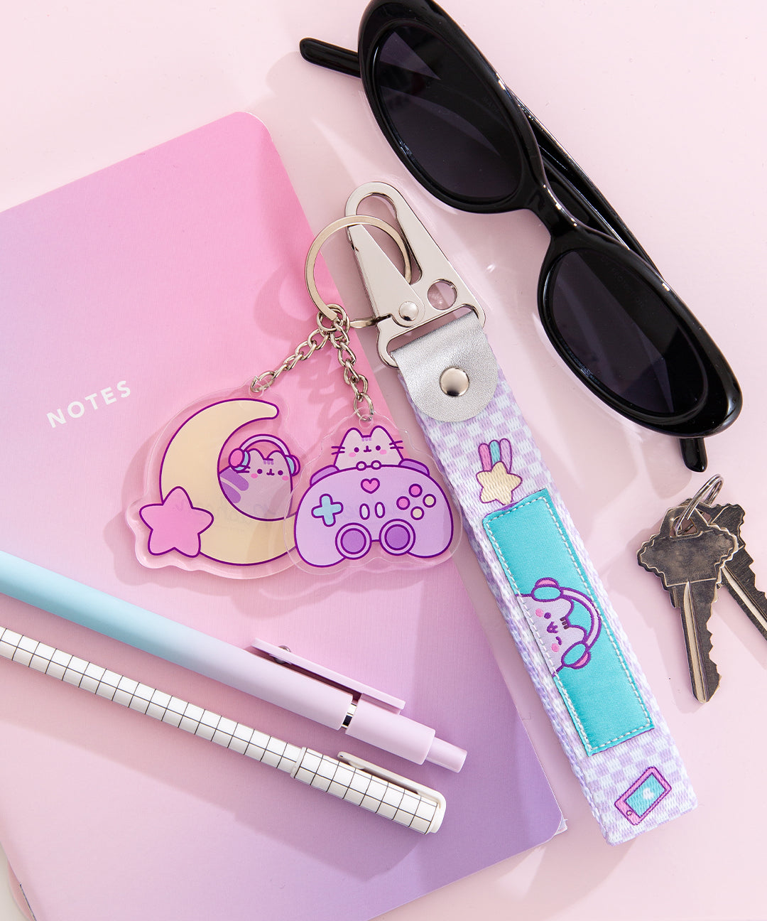 Front view of the Gamer Keystrap has a woven pattern and fits comfortably around the wrist. The two included key charms feature Pusheen with a gaming controller and headphones.
