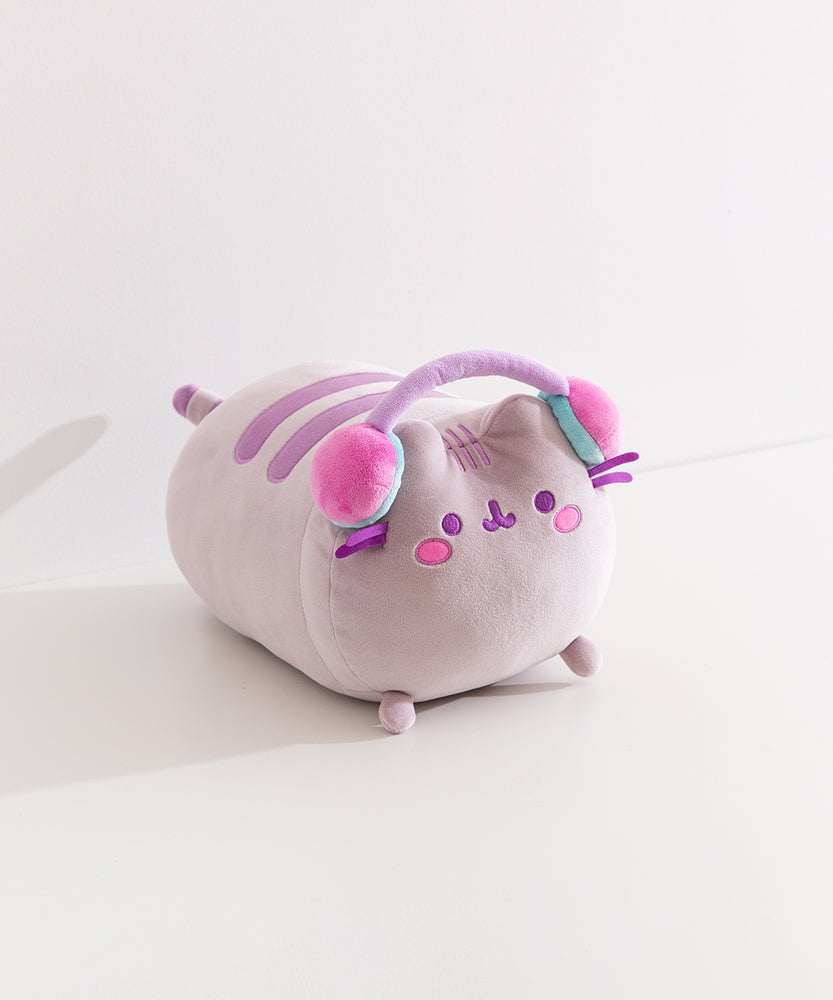 Side quarter view of the gaming squisheen. Pusheen the cat lazes while wearing a pair of multi-colored pastel headphones.