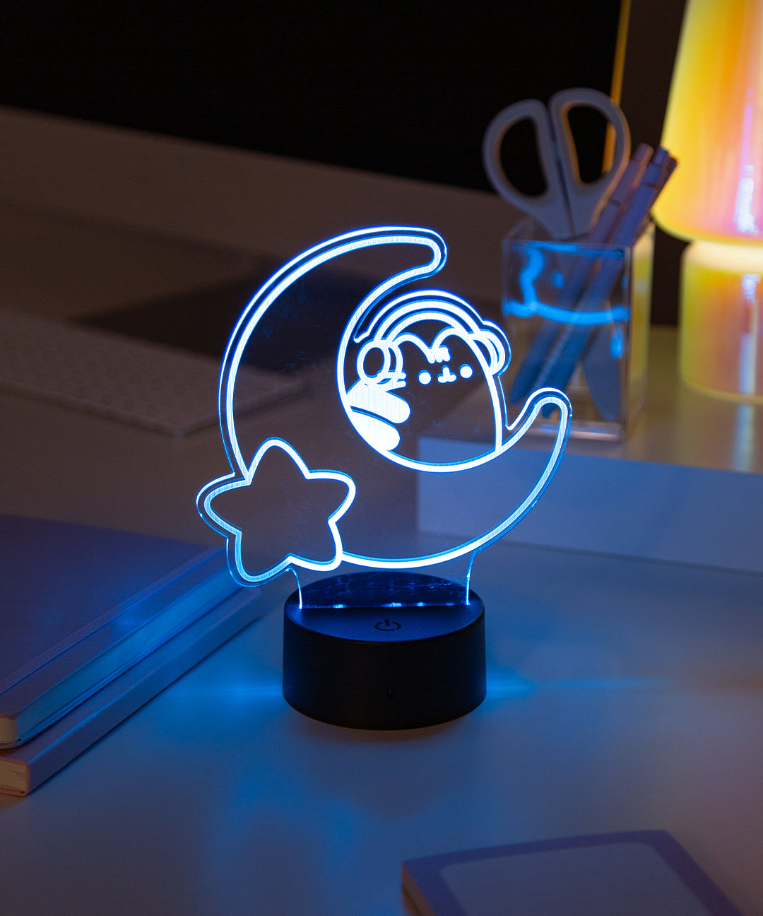 Neon light of Pusheen the Cat wearing headphones while sitting on a crescent moon. The LED light is set to the color white. 