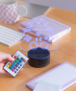 Model holds the remote to the Gamer Otaku Lamp next to the lamp to show the color and mode options.
