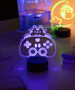 Purple Gaming-themed night light on a desk with blurred background.