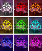 Color-changing LED lamp shaped like a gaming controller with a cat design on a dark background.