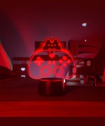 Red gaming controller-shaped light on a table with a dark background