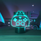 Teal blue gaming lamp of Pusheen the Cat and a gaming controller on a desktop.