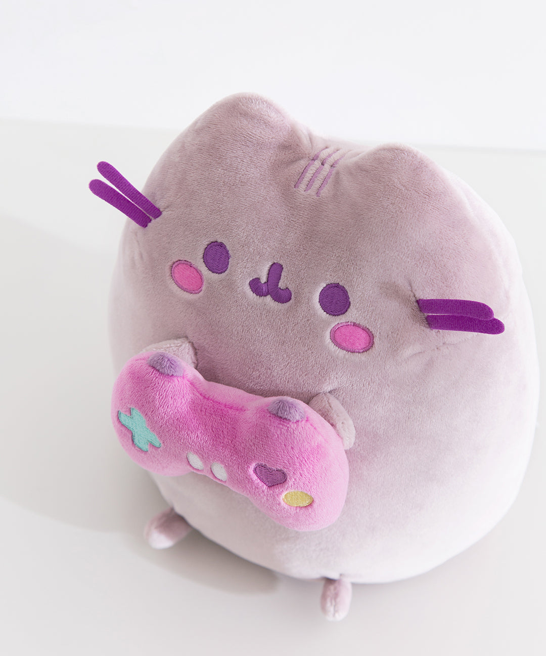 Close-up of the Gamer Pusheen Plush toy. The purple-hued cat has purple whiskers that extend off the front side of the plush.