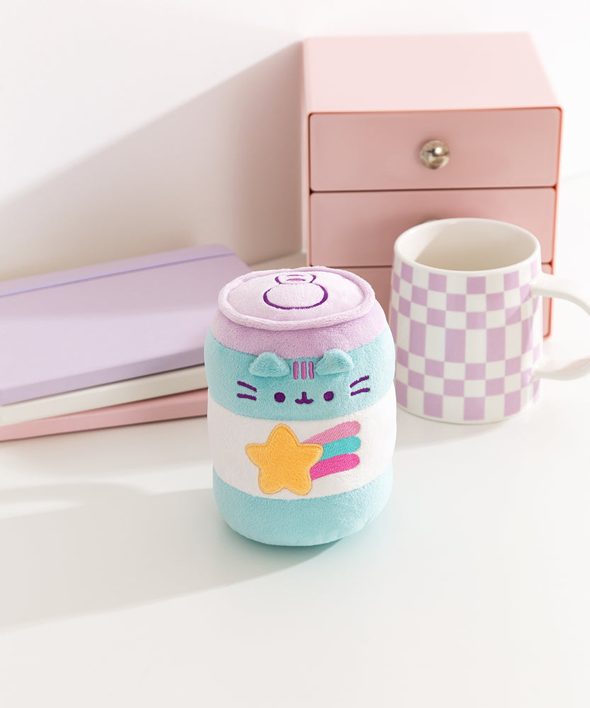 Gamer Pusheen Pop Sup Plush sits next to a coffee mug to demonstrate the size of the energy drink can inspired plush.