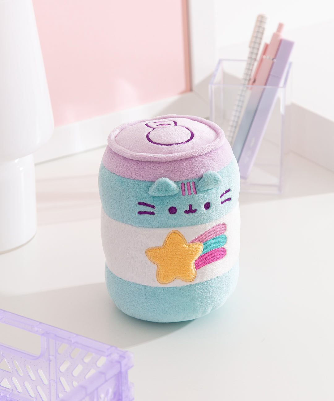 Front view of the Gamer Pusheen Pop Sip Plush. Pusheen the Cat takes the form of a blue and white striped energy drink with a purple lid ad pull tab. The front features Pusheen's face above a shooting star graphic. 