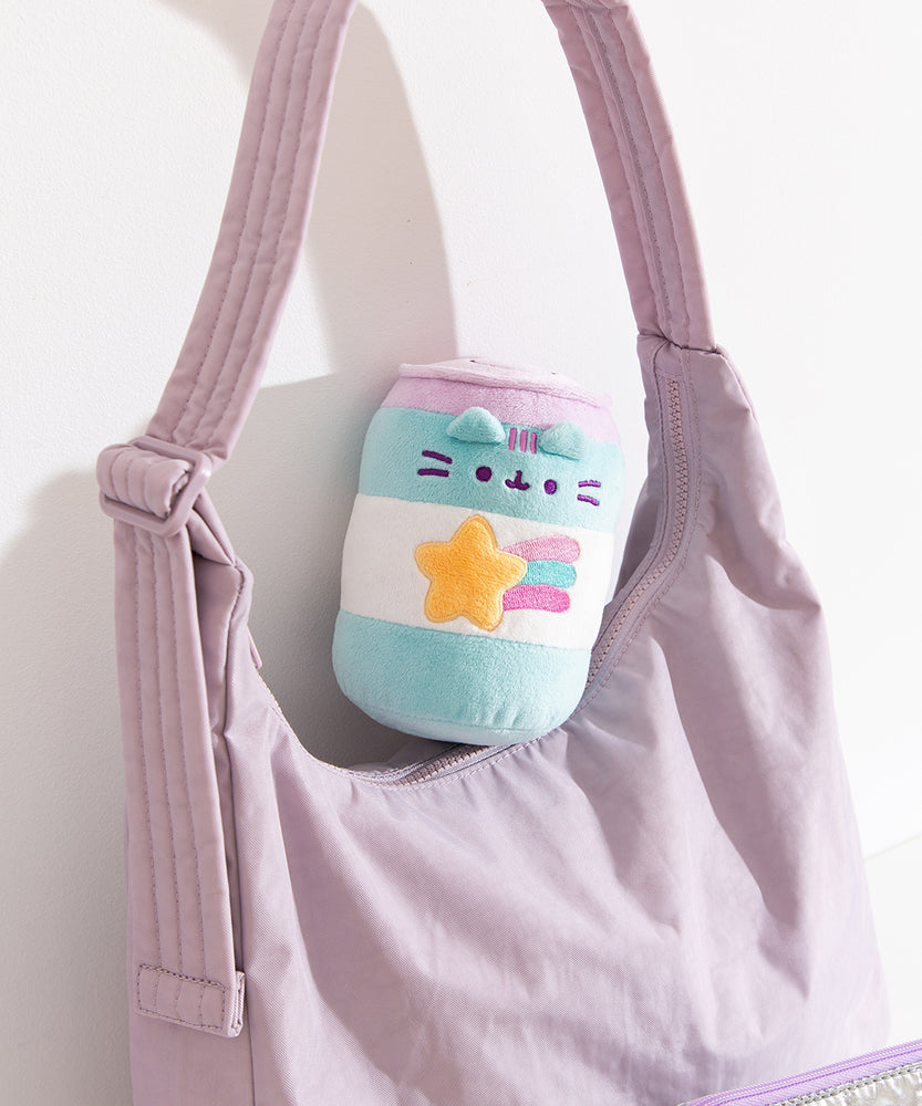 Pop Sip Plush can sits on top of a purple purse to show the small scale of the plush. 