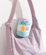 Pop Sip Plush can sits on top of a purple purse to show the small scale of the plush. 