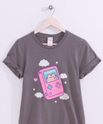 Close-up of the large graphic on the front of the Gamer Pusheen Retro Handheld Tee. Pusheen the Cat resides in a gaming console accented with pink, blue, and purple. 