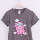 Close-up of the large graphic on the front of the Gamer Pusheen Retro Handheld Tee. Pusheen the Cat resides in a gaming console accented with pink, blue, and purple. 