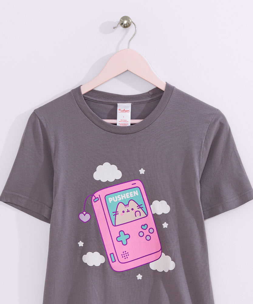 Dark gray t-shirt with a large graphic on the front center. The graphic shows Pusheen the Cat inside a pink gaming device with blue and purple plus sign and circle shaped buttons. 