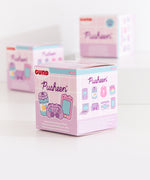 Side view of the gamer blind box packaging. The side view features graphics of all the known plush keychain styles with a darkened graphic with a question mark indicating the mystery plush style of the Gamer Surprise plush collection. 
