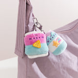 Close-up shot of Gamer Pusheen accessories: a bag of chips and an energy drink. The two blue and pink keychains are attached to a zipper on a purple handbag.  