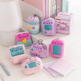 Gamer Pusheen Surprise Plush miniature plush keychains sit on a desktop. The seven blind box plush are accompanied by the box they come in. 