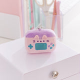 Close-up of the gaming console keychain plush. The light pink plush has Pusheen the Cat's facial features embroidered on the front along with various gaming buttons. 
