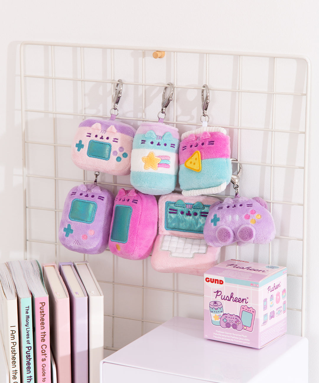Gamer Surprise Plush hang on a wire rack. The seven miniature plush hang in two rows and the blind box packaging sits below the gamer inspired plush keychains. 
