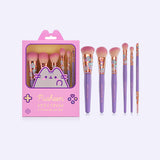 Gamer Pusheen 6-piece Makeup Brush Set next to its handheld gaming device imitation packaging. The brushes have a purple handle with golden metal ferrule with printed Pusheen graphics in mint green, purple, grey, and pink. The synthetic bristles are yellow and tipped with pink at the ends.