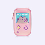 Front view of the pink brush bag that features Pusheen the Cat. The rectangular shape imitates a classic handheld gaming console. The case has a large square featuring Pusheen blushing and various gaming buttons.  