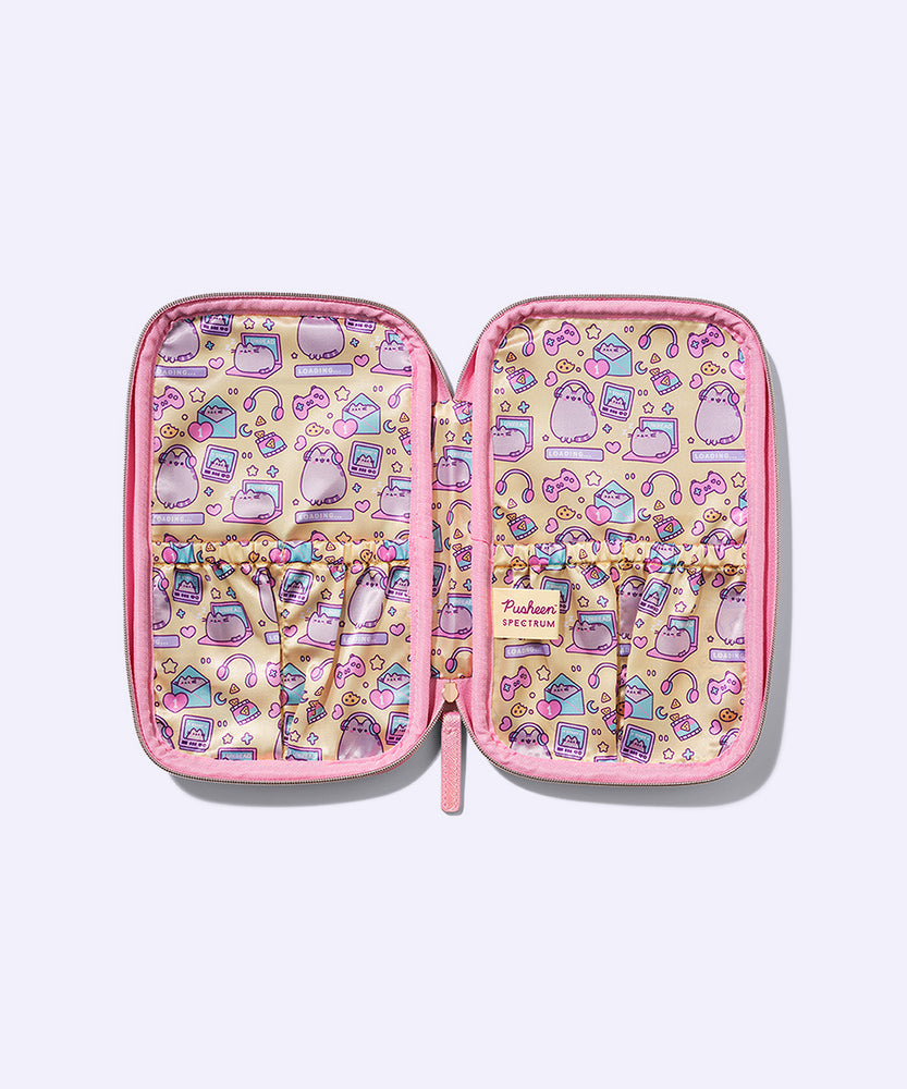 Interior view of the Gamer Pusheen Makeup Brush Bag. This storage compartment features an all over print of Pusheen wearing headphones, a gaming controller, hearts, stars, and more gaming icons. Both sides of the compact have an elastic section for makeup brush storage. 