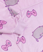 Close-up view of front pocket and the purple sleeve cuff ruching detail. The cuff is designed to stretch. Pusheen the Cat is shown blushing and leaping among pink gaming controllers.