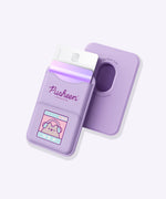 Front and back view of the purple Gaming Pusheen Magnetic Phone Wallet. The front has two pockets and a graphic of Pusheen the Cat winking while wearing headphones. The back shows an open hole in the rounded rectangular wallet so that the user can easily remove their cards from the pocket.  