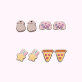 All earrings in Gaming Pusheen 4-Pack Stud Earrings Stud shown. From left to right and top to bottom, the stud earrings include Pusheen wearing headphones, a gaming controller, a shooting star, and pepperoni pizzas.  