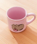 Back view of Pusheen pink mug. The light-pink cup features a grey and brown graphic of Pusheen relaxing with her own hot beverage in a pink mug. The graphic on the back matches the graphic on the front. 