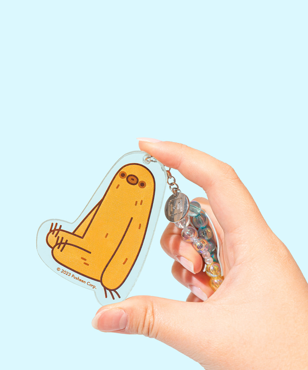 Model holds Sloth charm at the end of the beaded phone charm. Sloth is shown in yellow with dark gold hair accents with dark brown features and outline. The figure is set on a clear background.  