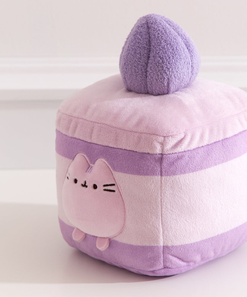 Close-up of the Pusheen plush on the Cake Squisheen. Pusheen's eyes, nose, and whiskers are embroidered in black while her three head stripes are a medium purple embroidery color.