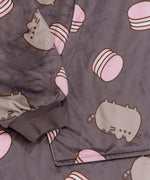 Close-up view of front pocket and the grey sleeve cuff ruching detail. The cuff is designed to stretch. A classic pose of Pusheen the Cat is accented by a pink macaron pattern. 