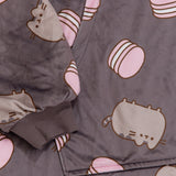 Close-up view of front pocket and the grey sleeve cuff ruching detail. The cuff is designed to stretch. A classic pose of Pusheen the Cat is accented by a pink macaron pattern. 