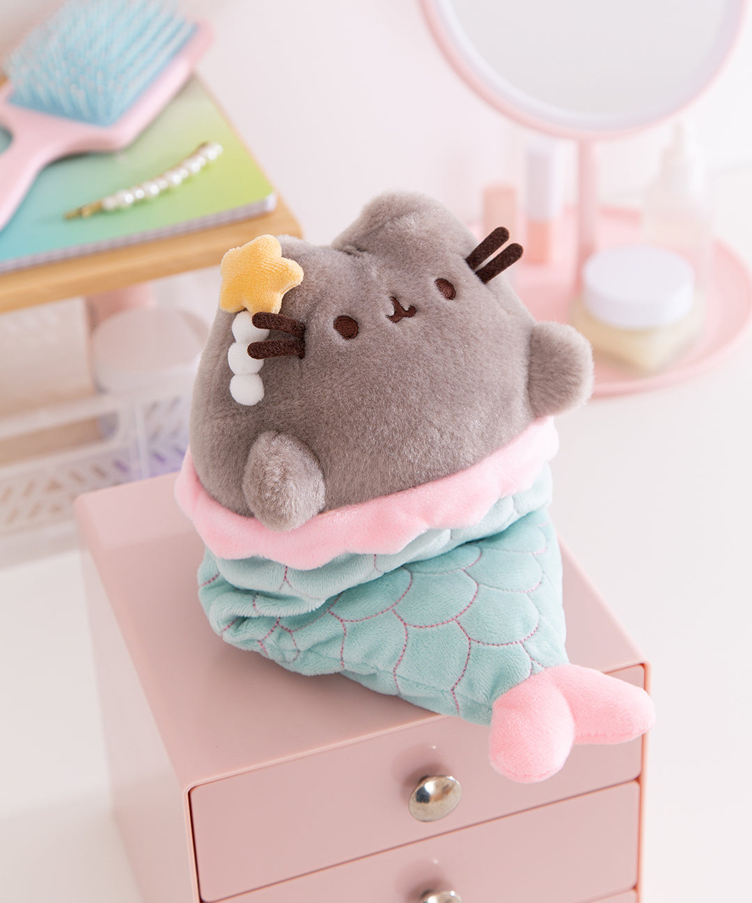 Close-up of the fluffy plush texture of the Mermaid Pusheen Plush. Next to the cat's right ear is a star and pearl clip.