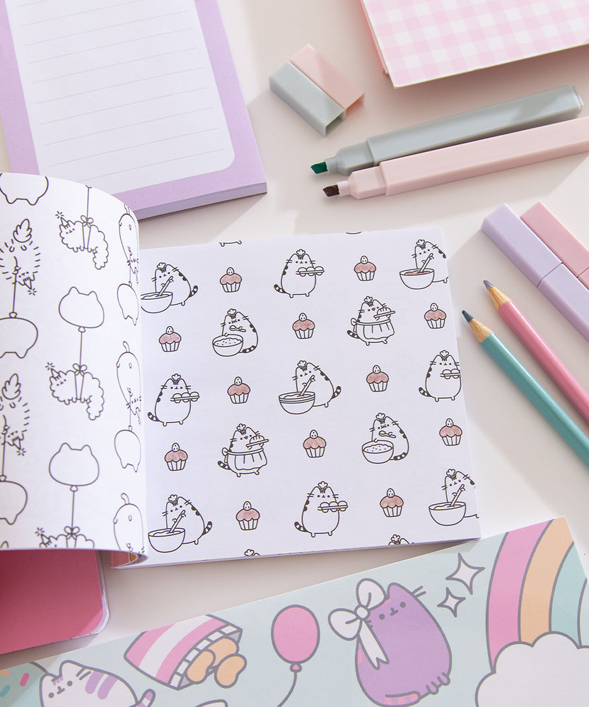 Mini Pusheen Coloring & Activity Book is opened to two white coloring pages with black graphics. On the left page is a repeating pattern of Stormy & Pip being carried by balloons. On the righthand page is a repeating pattern of Pusheen the Cat baking with cupcakes.
