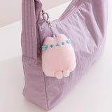 Pink plush keychain with blue accents attached to a purple bag.
