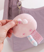 Model holding one of the front paws on the bag charm to show the embroidered paw print detail.