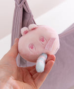 Pink plush keychain with paw prints held in a hand against a light background.
